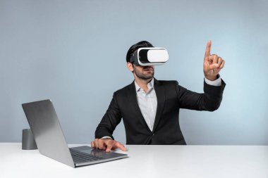 Bilgisayarla masada otururken ve VR gözlüğü takarken veri analizine bakan yetenekli bir iş adamı. Proje yöneticisi sanal gerçeklik sistemini kullanarak ya da metaevrende bağlantı kurarak çalışıyor. Sapma.