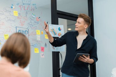 Profesyonel erkek lider projeye zihin haritası, renkli yapışkan notlar ve iş istatistiksel grafiği ile yatırımcı toplantısını dinlerken kendinden emin bir şekilde başlayarak başlıyor. Tertemiz..