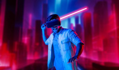 Lazer kılıcı tutan ve VR gözlük takan oyuncu. Beyaz adam, neon şatonun etrafında dikilirken görsel gerçeklik kulaklığı kullanıyor. Yenilik teknolojisi. Sapma.