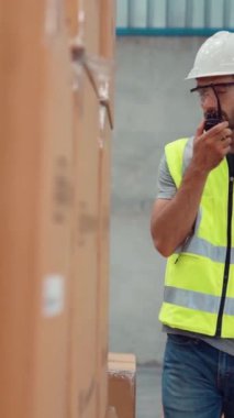 Profesyonel kargo işçisi başka bir işçiyle bağlantı kurmak için telsizle konuşuyor. Fabrika ve depo iletişim konsepti .