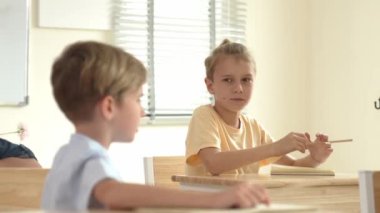 Beyaz bir çocuk ödevlerini yaparken ve açıklama dinlerken güzel bir öğretmen sınavı açıklıyor. Sınıfta not alırken ya da kağıda cevap yazarken öğretmenine bakan sevimli bir çocuk. Pedagoji.