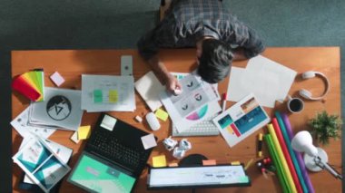 Toplantıda tasarımcı yazma ve logo grafiği tasarlamanın en üst görünümü. Renkli paletler üzerinde çalışan iş adamlarının yakınlaşması ve masaya kağıt ve ekipman ile yapışkan notlar yazmak. Sempozyum.