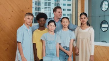 Mutlu öğretmen ve çeşitli öğrenciler kameraya gülümserken ayakta duruyorlar. Profesyonel akıllı eğitmen ve karışık ırk olan lise öğrencileri kameraya neşeli pozlar veriyor. Öğretim