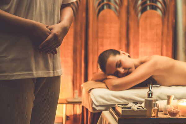 Caucasian woman customer enjoying relaxing anti-stress spa massage and pampering with beauty skin recreation leisure in warm candle lighting ambient salon spa at luxury resort or hotel. Quiescent