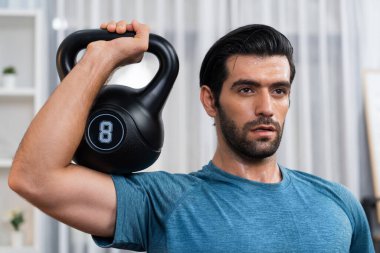 Atletik vücut ve aktif sporcu, sağlıklı vücut çalışma yaşam biçimi konsepti olarak eğlence evinde kas kazancı için kettlebell ağırlığını kaldırıyor..