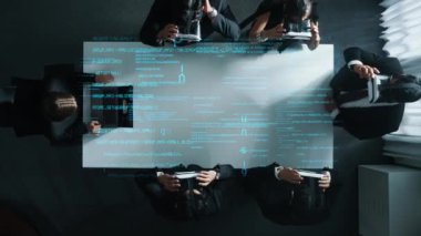 Profesyonel iş adamlarının yukarıdan aşağı görüntüsü VR kulaklık takarken mühendislik komut hologramı etrafında durur ve yönetici dizüstü bilgisayardan elde edilen verileri manipüle etmek için el hareketleri kullanır..