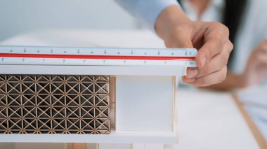 Profesyonel mimar erkek mühendisin yakın çekim görüntüsü modern ofisteki ev modelini ölçmek için cetvel kullanır. Yaratıcı yaşam ve tasarım konsepti. Geçmişi bulanıklaştırıyor. Eline odaklan. Tertemiz.