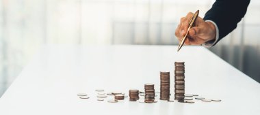 Büyüyen madeni para yığını iş yatırımını ve ekonomik büyümeyi simgeliyor. Finansal hedefe ulaşmak ve maksimum kâr sağlamak için finansal planlama yapan iş adamları. Kurnaz.