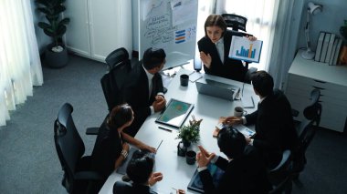 Akıllı iş kadınlarının en üst görüşü çeşitli iş adamlarına satış tablosunun arttığını gösterirken, bir grup farklı iş adamı da masada belgelerle hisse yatırım verilerini dinleyip analiz ediyor. Müdürlük.