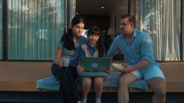 Father, mother and daughter focus laptop at terrace with garden view outside house. Parent use outdoor activity to communicate young generation about environment care cross generation gap. Divergence. clipart