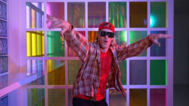 Komik break dansçı kameraya bakarken hiphop 'a doğru serbest adım atıyor. Çılgın mutlu hipster dans edip sokak dansı yaparken Led ışığında günlük kıyafet ve güneş gözlüğü takıyor. Mutluluk.