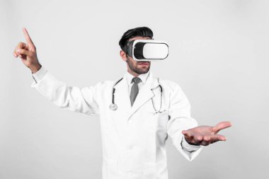 Kafkasyalı doktor ayakta dururken tıbbi verileri gösterip seçiyor. Meta-evreni veya görsel gerçeklik programını bağlamak için laboratuvar önlüğü ve sanal gerçeklik gözlüğü takan yakışıklı bir doktor. Teknoloji yeniliği. Sapma.