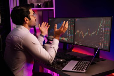 Akıllı tüccar işadamı, karanlık oda gecesinde neon ışıklı ofisteki arama pazarında yüksek kârla ekranda bilgisayar ve bilgisayar üzerinde dinamik borsa yatırımları üzerinde yoğunlaşıyor. Tahmin et..