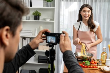 Kameraman, şef etkisinde olan kadına makarna pişiren, domates soslu spagetti hazırlayan, içerik tarifini saran, modern stüdyoda özel sağlıklı yemekler sunan bir kayıt yapıyor. Varsayım.