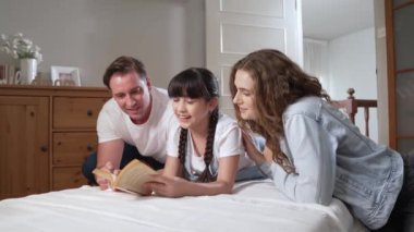 Çocukluk hikayeleri anlatan uyku zamanı, anne ve baba rahat ve rahat yatak odasındaki küçük kızlarına birlikte fantezi kitabı okuyorlar. Modern aile eğlencesi. Titiz