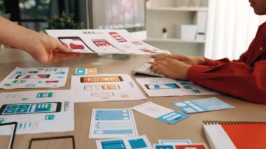 Mobil uygulama için kullanıcı arayüzü prototipini ofis çalışanlarına sunan harika bir şirket çalışanı. UX UI tasarımcısı kağıt üzerinde simge tasarımının işlevini açıklıyor. Sinerjik