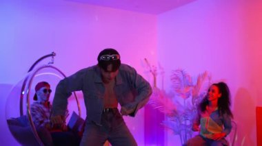 Çok kültürlü bir arkadaş kürsüde otururken Asyalı yetenekli bir dansçı modern müziğe geçiyor. Profesyonel dansçı, hipster takımı tezahürat yaparken ve desteklerken enerjik adımlar atıyor. Mutluluk.