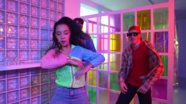 Değişik takımlarla dans ederken süslü gözlük takan yakışıklı hippi serbest stil müzikle mutlulukla dans ediyor. Beyaz hipster kulüpte parlak neon ışıkta sokak dansı yapıyor. Mutluluk.