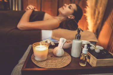 Aromaterapi masajı ambiyansı ya da spa salonu kompozisyon düzeneği bulanık kadınlara odaklı dekor mumları ve spa aksesuarları ile tatil köyü veya otel arka planında keyifli aroma spa masajı yapan. Sessiz.