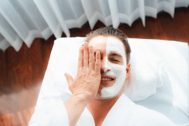 Kaplıca salonunun sakin atmosferi, insan müşterisi modern gün ışığında lüks yüz kremi masajıyla kendini yenileme zevkine kapılıyor. Yüz bakımı ve güzellik konsepti. Sessiz.