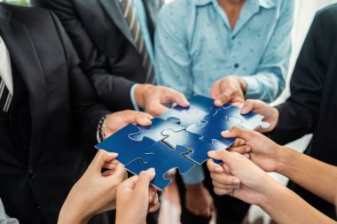Çok ırklı iş adamları yapboz parçalarını tutuyor ve onları etkili çözüm çözümleri olarak birleştiriyor takım çalışması, ortak görüş ve çeşitli yetenekleri birleştiren ortak hedef. Çok titiz.