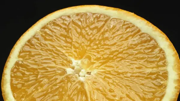 Stock image A macrography capture of an orange slice, placed against a sleek, isolated black backdrop, unfolds as a visual masterpiece of citrus allure. A slice of orange with black background. Comestible.