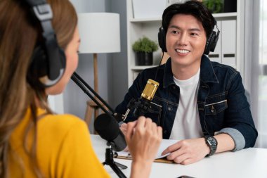 Gülümseyen radyo etkili sunucusu kulaklık takıyor kadın konuşmacı ile röportaj yapıyor sosyal medya internet sitesinden dinleyicilere bilgi paylaşıyor stüdyo kaydında sabah canlı yayın kanalı. İnfobahn.