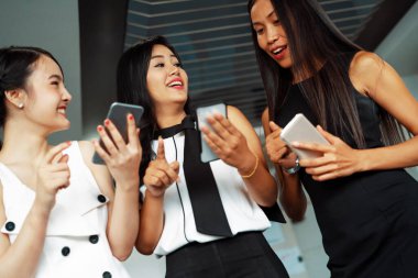 Üç kadın arkadaş ellerinde cep telefonuyla sohbet ediyorlar. Sosyal medya, dedikodu haberleri ve online alışveriş kavramı. uds