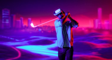 Sanal dünyaya girmek için sanal gözlük takan beyaz bir adam metaevrende golf oynuyor. Sanal gerçeklik gözlüğü kullanan yakışıklı oyuncu neon golf sahasına giriyor. Yenilik. Spor. Sapma.