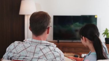 Grandfather and granddaughter eat french fries watch interesting entertainment on TV. Senior use technology communicate with young generation cross generation gap strengthen family bond. Divergence.