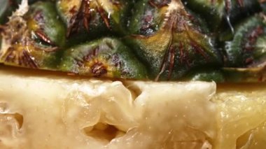 Taze ananaslı ve ayrı siyah arkaplanlı bir ananas dilimli videoyu kapat. Kaba ve balmumu kabuğu, dikenli yeşil yapraklardan bir taç, yemek fotoğrafçılığı. Geliştirilebilir.