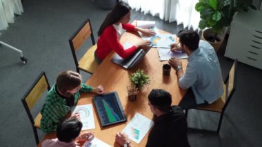 Proje yöneticisinin üst görünümü toplantıda yatırımcılara mali grafik sunuyor. Profesyonel pazarlama ekibi dizüstü bilgisayardan finansal istatistiklere bakarken finansal fikir üretiyor. Cemaat.