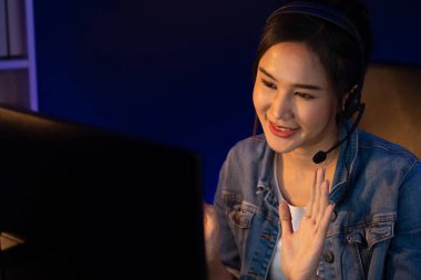 Sunucu kanalı Asyalı etkileyicisi canlı yayında konuşuyor. Sosyal medyada kulaklık takıyor, bilgisayar kaydı yapıyor, dinleyicileri selamlıyor ve Neon Modern Stüdyoları 'nda online olarak koçluk yapıyor. Taktik.