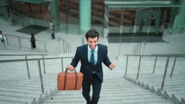 Terfi alma, satışları artırma, maaşları artırma konusunda iyi haberleri kutlamak için dans eden mutlu iş adamı şehirde geçmişi bulanık bir şekilde merdivenlerden çıkarken. Neşeli bir ruh hali. Sevinçli..