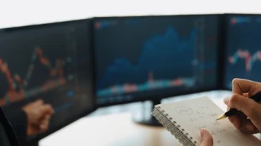 Borsa pazarlama şirketindeki iş yatırımcıları, zarar için mum bar fiyatlarını analiz eden monitörlere bakarak hisse senedi pazarlamasını not alıyor ve analiz ediyor. Filizlenen