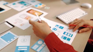 Mobil uygulama için kullanıcı arayüzü prototipini ofis çalışanlarına sunan harika bir şirket çalışanı. UX UI tasarımcısı kağıt üzerinde simge tasarımının işlevini açıklıyor. Sinerjik