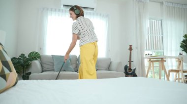 Gülümseyen kulaklıklı hizmetçi yerleri temizlerken müzik dinliyor. Oturma odasında dans ederken yerleri paspaslayan Kafkasyalı mutlu bir anne. Gülümseyen anne ev işi yapıyor. Yaşam tarzı. Pedagoji