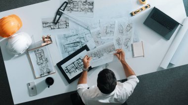 Yetenekli inşaat mühendisinin ev modeline bakarken oturup fikir yazması. Mimarın ya da tasarımcının yaratıcı bina inşaatını planlama ve düşünme havadan görünüşü. Hizalama.