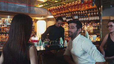 VIP grubu, barın önünde oturmuş arkadaşlarıyla ya da barmen hazırlarken karışık punç kokteyli içen çiftle yaşam tarzı seyahatlerini tartışıyor tezgahın üzerinde arka taraftaki süslü Noel ağacını hazırlıyor. Vinosity.