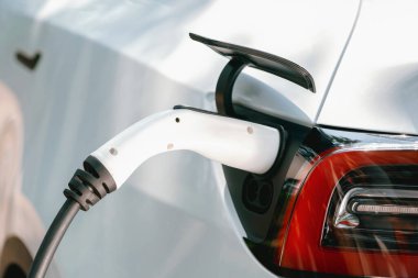 Temiz ve sürdürülebilir enerji kullanarak şarj olmak için EV şarj cihazına EV şarj cihazı takıldı. Doğal koruma ve çevre dostu araba yolculuğu konsepti. Yükselt