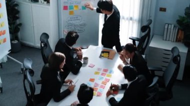 Üst düzey iş adamı, iş adamlarının fikir alışverişi yaparken zihin haritası ve renkli yapışkan notlarla beyaz tahtaya yapışkan notlar koydu. Yönetici pazarlama fikrini seçti. Müdürlük.