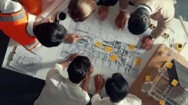 Becerikli mühendis ekibinin ev inşaatından bahsedişinin en alt görüntüsü. Mimar ya da tasarımcı grubunun planlar hakkında beyin fırtınası yapmak için tartışan ve yazan hava görüşü. Hizalama.