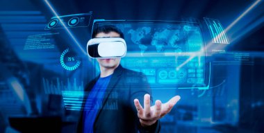 VR gözlüklü proje yöneticisi elinde mali tablo ve ofiste parlayan mavi ışık tutuyor. Yetenekli iş adamı artırılmış gerçeklikten elde edilen verileri kullanarak pazarlama stratejisini kontrol edip planlıyor. Yaratıcılık.