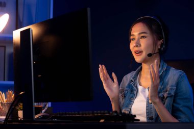 Sunucu kanalı Asyalı etkileyicisi canlı yayında konuşuyor. Sosyal medyada kulaklık takıyor, bilgisayar kaydı yapıyor, dinleyicileri selamlıyor ve Neon Modern Stüdyoları 'nda online olarak koçluk yapıyor. Taktik.