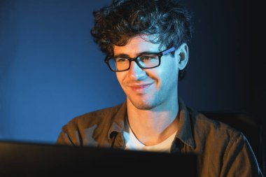 Neon Light Modern Ofis 'te yaratıcı bir başlangıç projesi için bilgisayara odaklanan gülümseyen genç iş adamı. Düşünüyorum da, pazarlama ağı yaratıcıdan pazar kanalı tasarım konseptine çevrimiçi planlama. Toplayıcı.