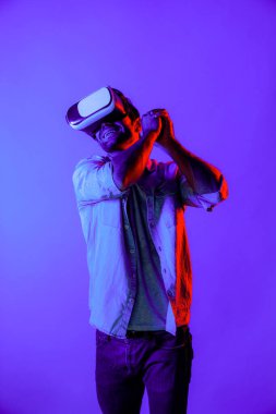 VR gözlüklü beyaz adam golfte hareket ediyor ve neon arka planda duruyor. Profesyonel oyuncu sanal dünyaya fütüristik teknoloji yeniliğiyle giriyor. Sapma.
