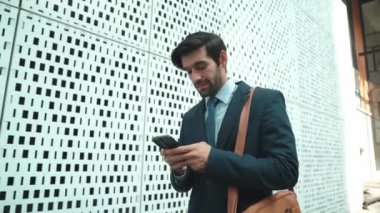 Akıllı iş adamı iş yatırımları hakkında konuşmak için telefonu kullanıyor. İş planı, pazarlama stratejisi ya da çalışma hakkında konuşmak için akıllı telefonla konuşurken sokakta yürüyen mutlu bir yönetici. Sevinçli..