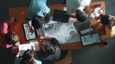 Yetenekli iş adamlarının tablet tutması ve planlara bakması. Masada dizüstü bilgisayarla dururken mimarın tasarım ve planlama bölümünün havadan görüntüsü. Sempozyum.