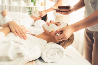 Kaplıca salonunun sakin atmosferi, modern gün ışığında lüks yüz kremi masajıyla gençleşmeye hevesli çiftler. Yüz bakımı ve güzellik konsepti. Sessiz.