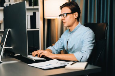 Akıllı iş adamı iş paragrafı dinamik pazarlama analizi planını analiz ediyor. Kağıt kağıtları ve bilgisayar monitörü raporlarını gece evdeki belge verileriyle karşılaştırmak için hazırlıyor. Bireysel.